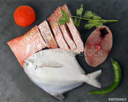 White pomfret Spanish mackerel red snapper fish cleaned descaled degutted  sliced fillet pieces on black marble