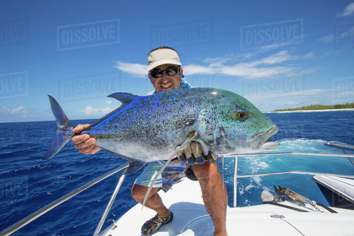 Fisherman holds a fresh caught Jack Fish; Tahiti